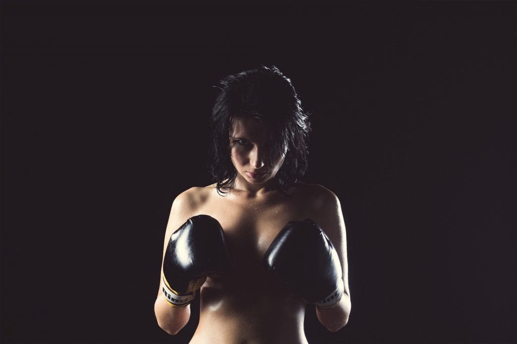 femmes seins nues portant des gants de boxes pour protéger sa poitirne